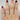 Tyra 7mm 14kt White Gold Round Moissanite and Diamond Vine Twist Bridal Set displayed on a woman's hand against a blurred background