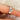 Rose gold ring with three moissanite on a finger against a neutral background