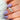 Hand with purple nail polish wearing a rose gold ring with trilogy stones on a soft fabric background