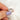 Rose gold ring with three large moissanites held by a hand with purple nail polish on a white background