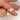 Gold ring with a oval-shaped diamond with cluster stones on a finger against a blurred background