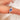 cornflower blue sapphire trilogy ring on pointer finger and white background